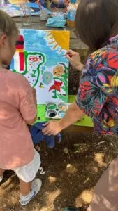 Une educatrice accompagne un enfant pour peindre une oeuvre sur la paix