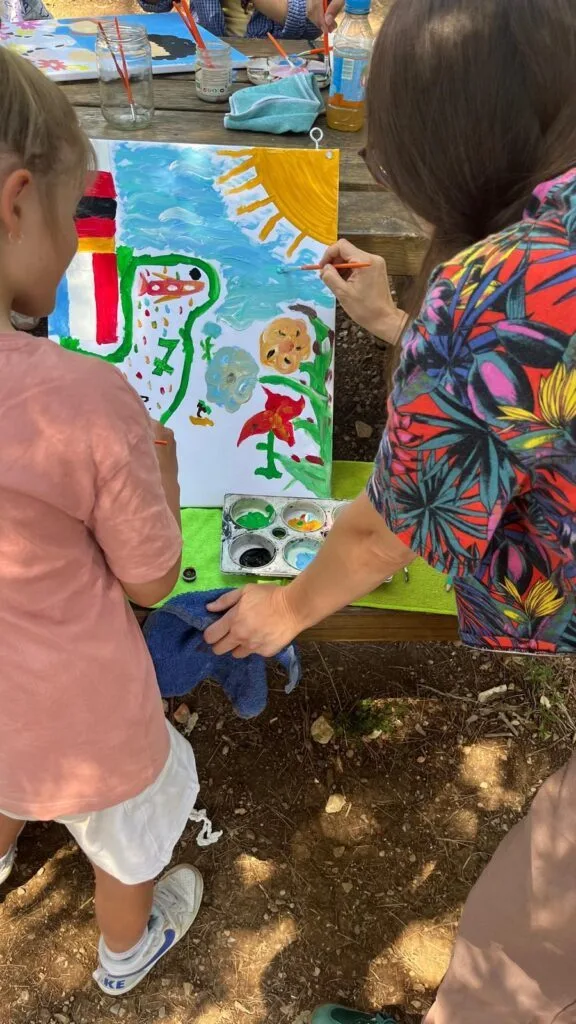Une educatrice accompagne un enfant pour peindre une oeuvre sur la paix